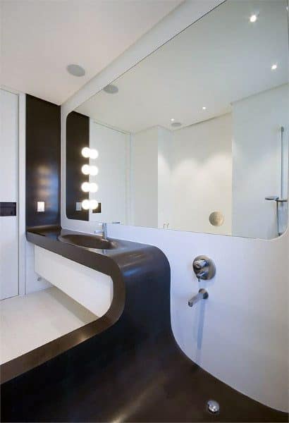 Modern bathroom with custom black and white curved sink and large wall mirror.