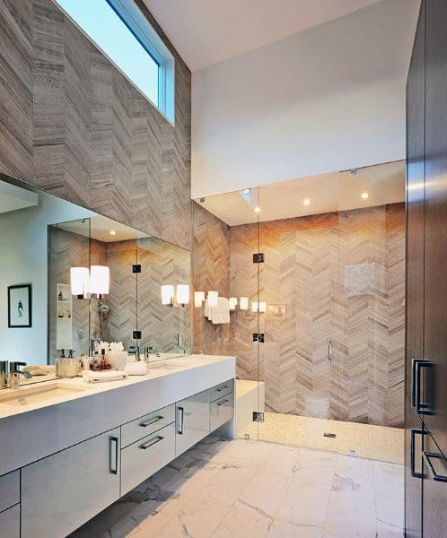 Modern bathroom with large mirror, double sink, and herringbone tile shower