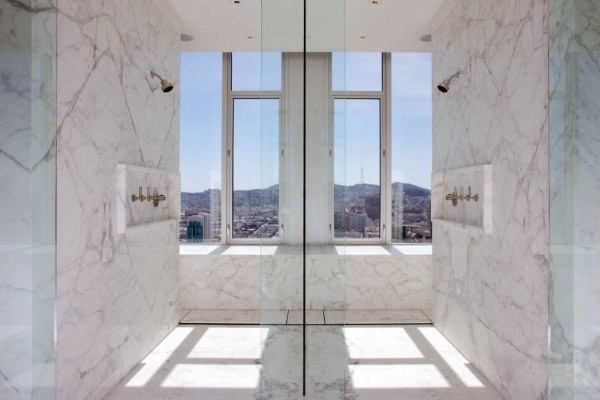 Marble shower with dual showerheads, a large window, and a scenic city view