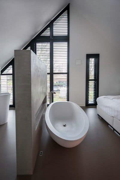 Modern attic bathroom with a freestanding tub and large triangular windows