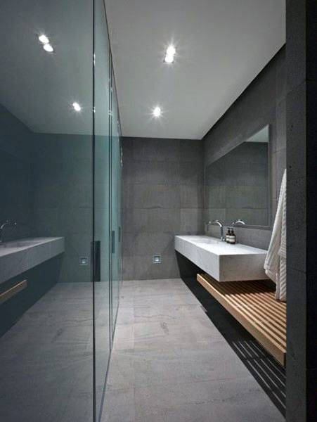 Modern bathroom with glass shower, long sink, and wooden bench underneath