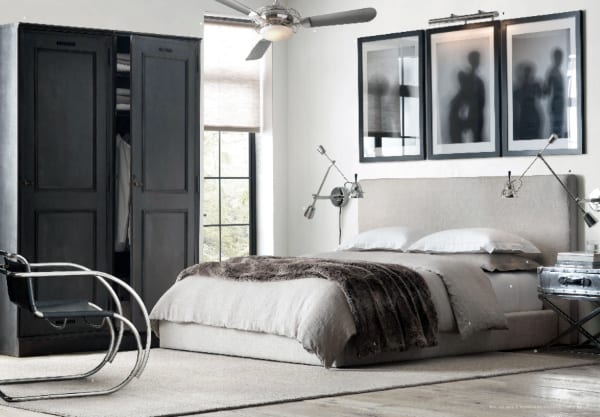 Modern bedroom with neutral tones, upholstered bed, black wardrobe, and abstract framed art.