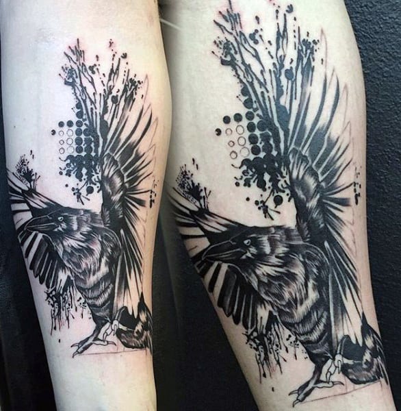 Black and white raven tattoo with abstract splashes on an arm