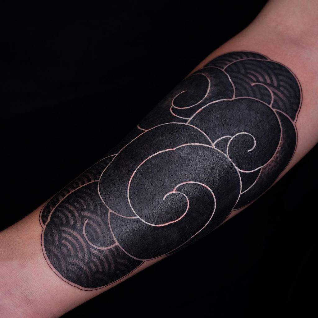 Black and dark gray swirl tattoo with intricate patterns on a forearm
