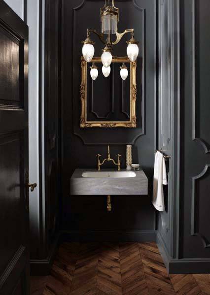 Luxurious black bathroom with ornate gold mirror, vintage chandelier, and sleek gray sink.