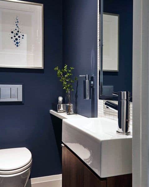 Contemporary bathroom with navy walls, white sink, and framed modern art.