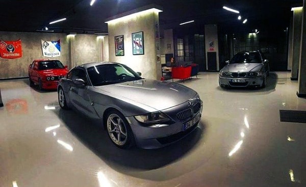 A sleek BMW-themed garage featuring polished floors, stylish lighting, and a cozy lounge area.