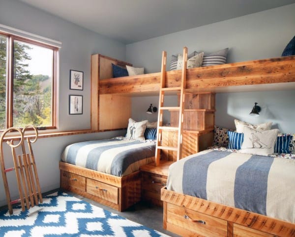 Cozy bedroom with wooden bunk beds, blue-striped bedding, tree views, ski decor, and a geometric rug