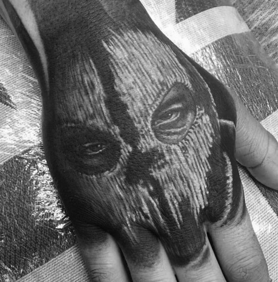 Intense Call of Duty Ghost mask tattoo on the hand, featuring detailed black and grey shading with piercing eyes for a bold and striking look.