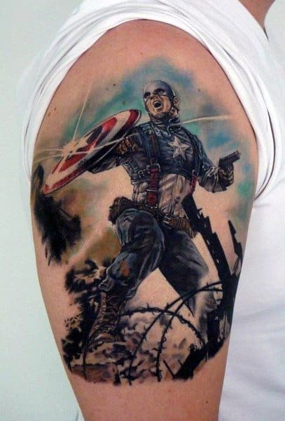 Vibrant upper arm tattoo of Captain America in battle stance, holding his iconic shield, surrounded by debris and barbed wire.