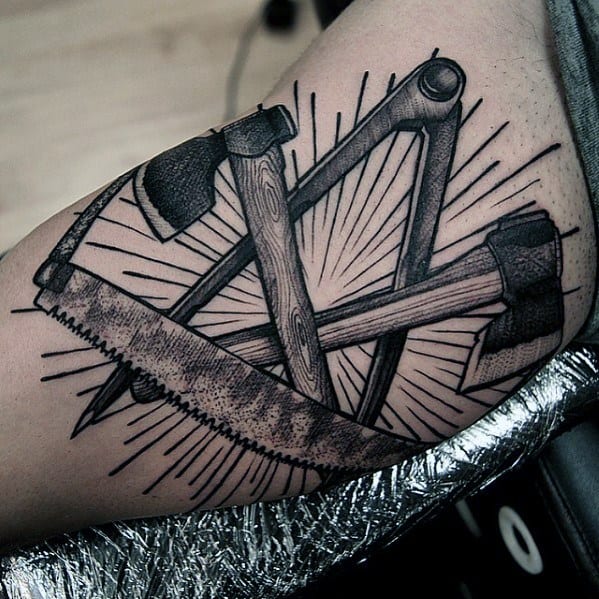 Bold blackwork tattoo featuring crossed axes, a saw, and a brace drill, symbolizing craftsmanship, strength, and dedication to woodworking.
