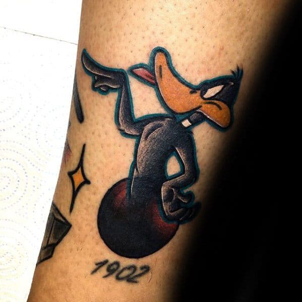 Bold and cheeky tattoo of Daffy Duck smirking and pointing, sitting on a bomb with the number 1902 inked below.