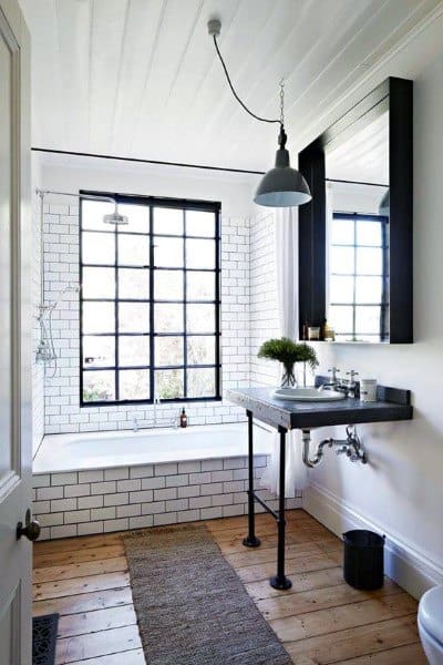 Industrial-style bathroom with subway tile, black-framed window, and shiplap ceiling.
