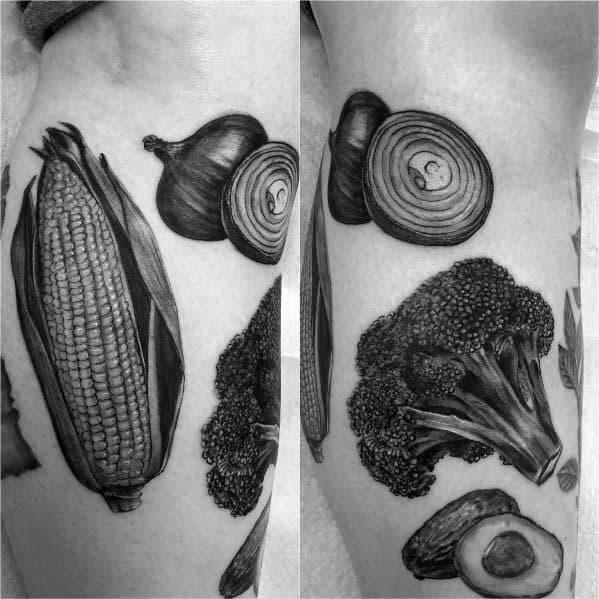 Black and gray realistic tattoo of corn, onions, broccoli, and mushrooms, arranged in a detailed vegetable-themed design on the skin.