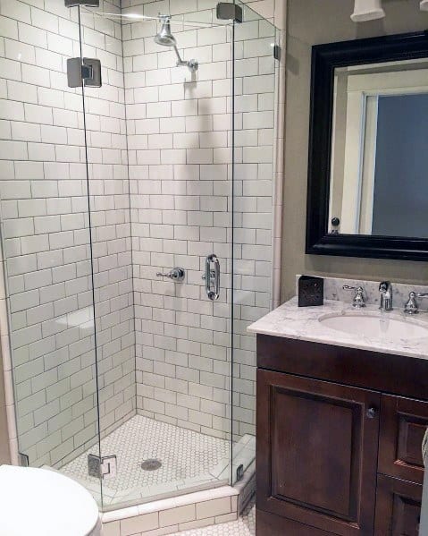 Corner bathroom with a glass shower enclosure, white tiled walls, and dark wood vanity with a marble countertop