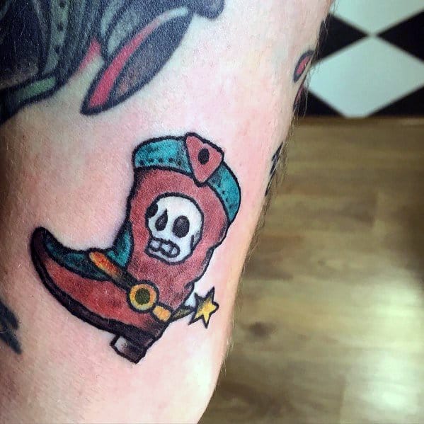 Colorful cowboy boot tattoo with a skull design and a spur, blending Western and gothic elements for a bold and unique style.