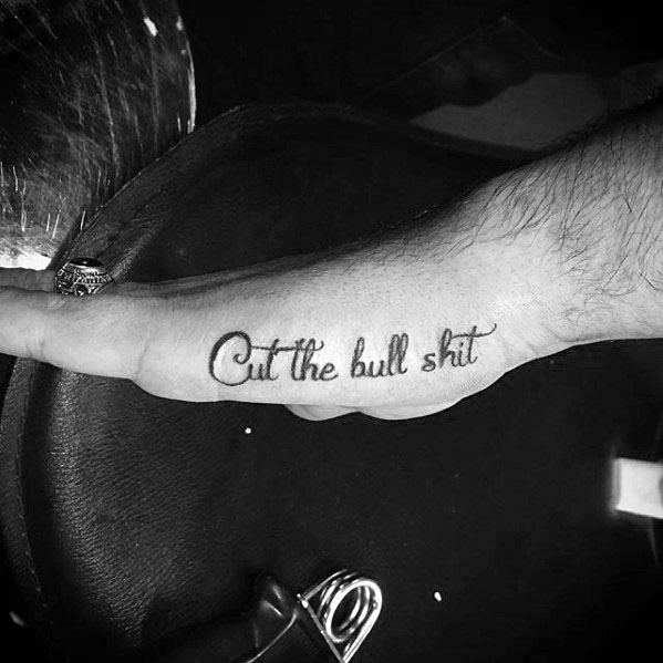 Side hand tattoo for men with the phrase Cut the bull shit in cursive script inked along the outer edge of the hand.