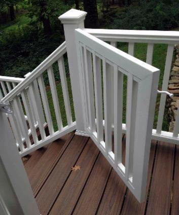White gate on a wooden deck, slightly ajar, revealing a grassy yard beyond