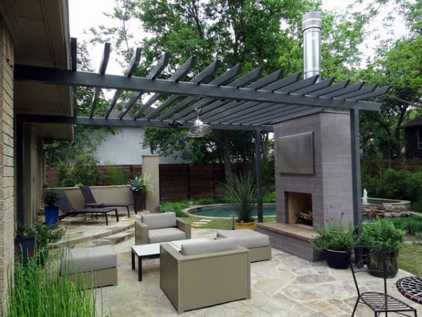 Modern pergola with gray slatted roof, outdoor fireplace, pool, and comfortable seating area.