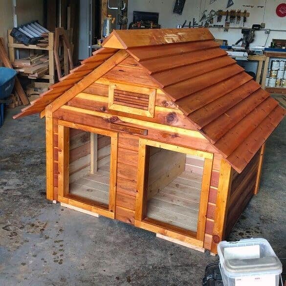 Wooden dog house with a pitched roof in a workshop setting, perfect for your beloved dog