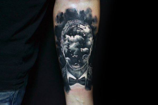 Surreal black and grey tattoo of a man in a suit with his face replaced by clouds and sky, blending realism and dreamlike elements.