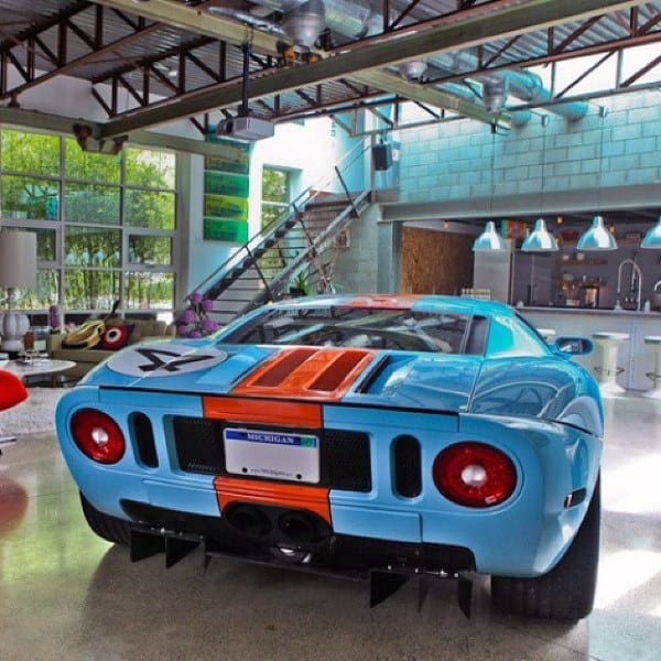 Modern garage lounge featuring a Ford GT, vibrant decor, and a stylish open-concept living space.