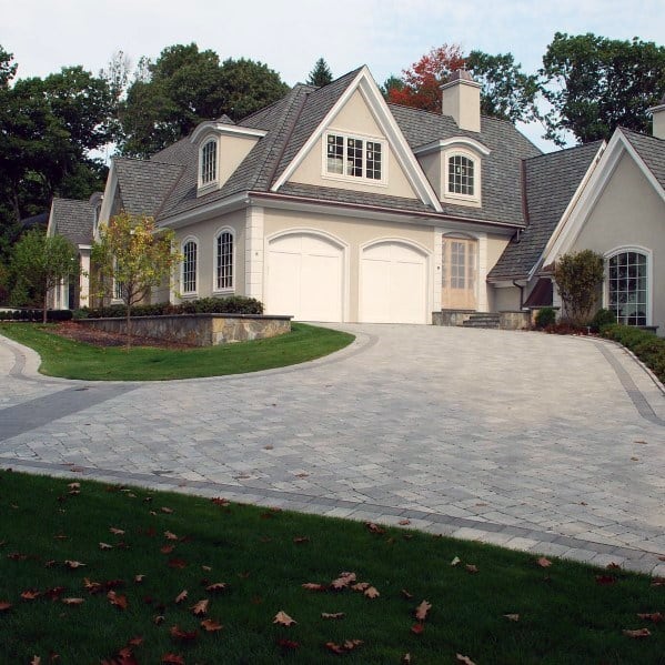 Curved brick-paved driveway with a smooth and elegant design leading to a classic-style home.