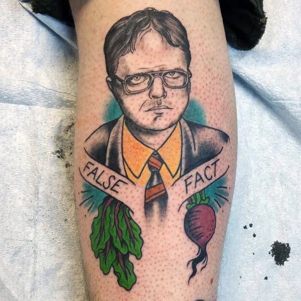 Color tattoo of Dwight Schrute with a serious expression, framed by "False" and "Fact" banners, featuring a beet and lettuce on a leg.