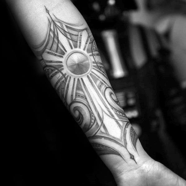 Filipino sun tattoo on the forearm with soft shading, long radiant beams, and swirling tribal patterns surrounding the circular center.