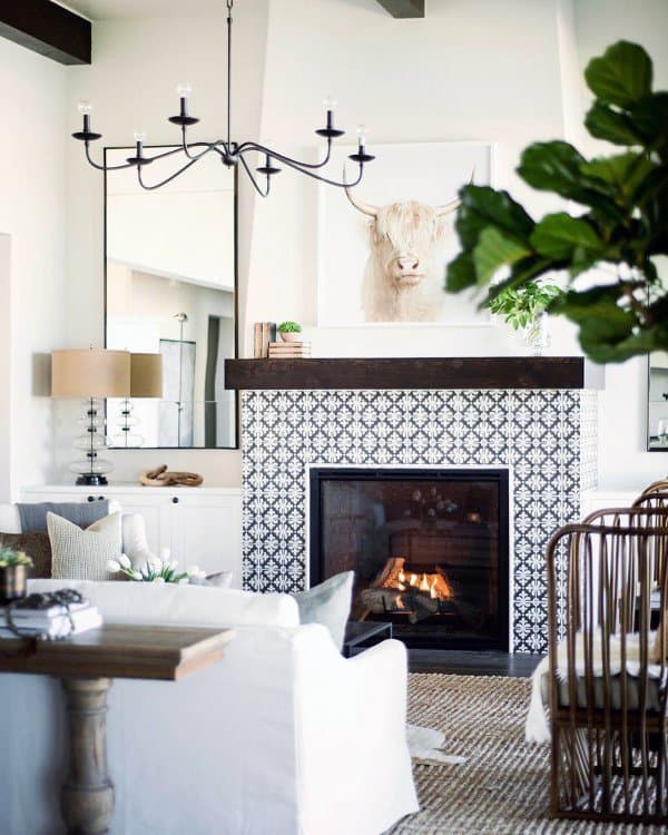 Tiled fireplace with a dark wooden mantel, modern farmhouse decor, and a cozy living room setting.