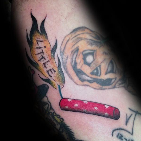 Tattoo of a lit firecracker with a burning matchstick that reads "LITTLE," featuring bold red and yellow tones with a spooky pumpkin design.