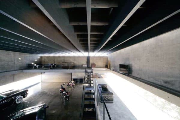 Spacious garage with cars and motorcycles, featuring concrete walls and a high ceiling