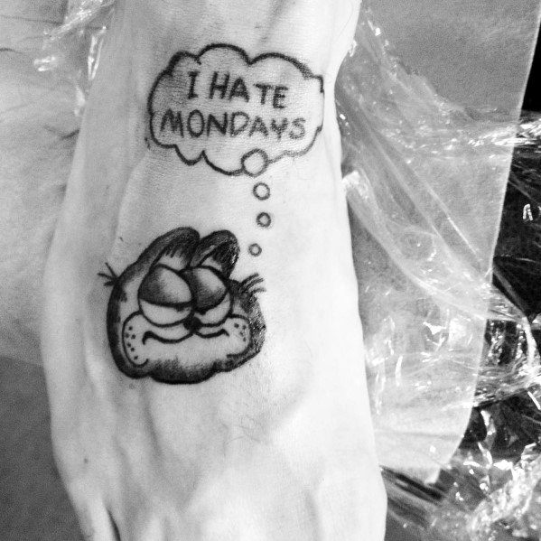 Black and gray Garfield tattoo with a thought bubble saying 'I Hate Mondays'—a classic, relatable design for humor lovers.