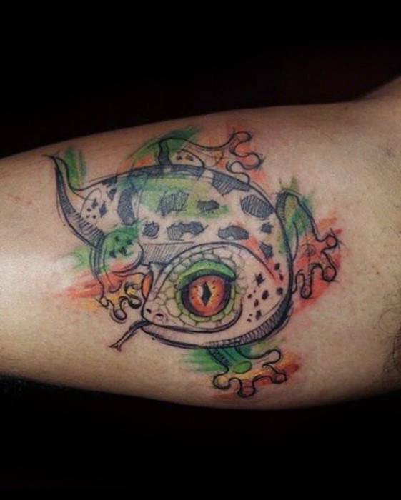 Artistic gecko tattoo with bold orange eye, green spots, and sketch-style lines on a splash of red and green watercolor background.
