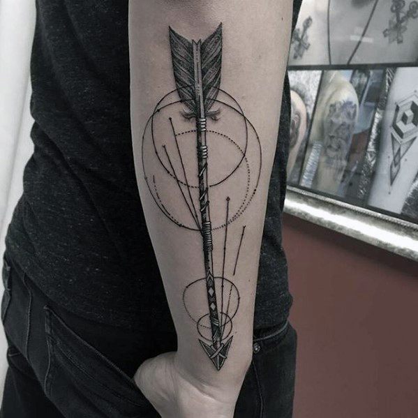 Detailed geometric arrow tattoo featuring precise circles, fine line accents, and realistic feather detailing on the forearm.