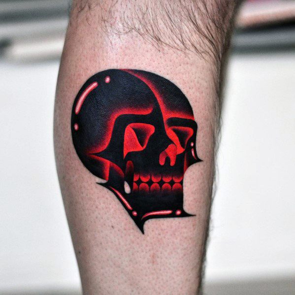 Bold gradient skull tattoo with sharp red and black contrasts, creating a glowing, futuristic metallic effect on the calf.