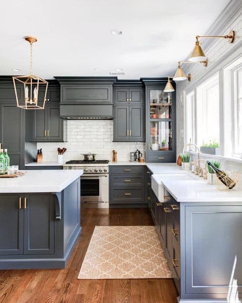 Navy grey kitchen with white countertops, brass fixtures, and hardwood flooring.