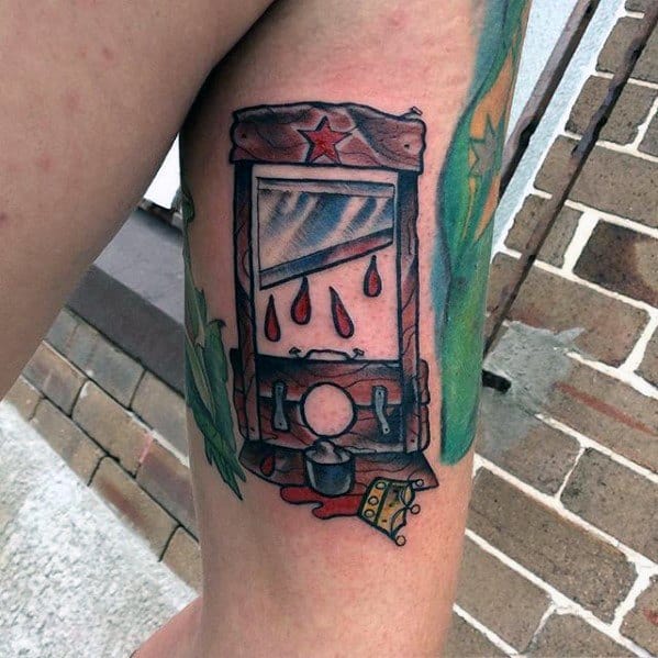 Colorful guillotine tattoo with dripping blood, a red star on top, and a severed crown lying beneath the blade.