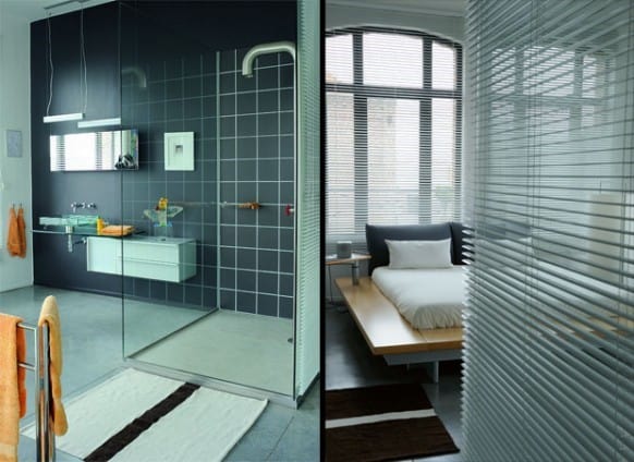 A modern bathroom and bedroom separated by glass doors with blinds