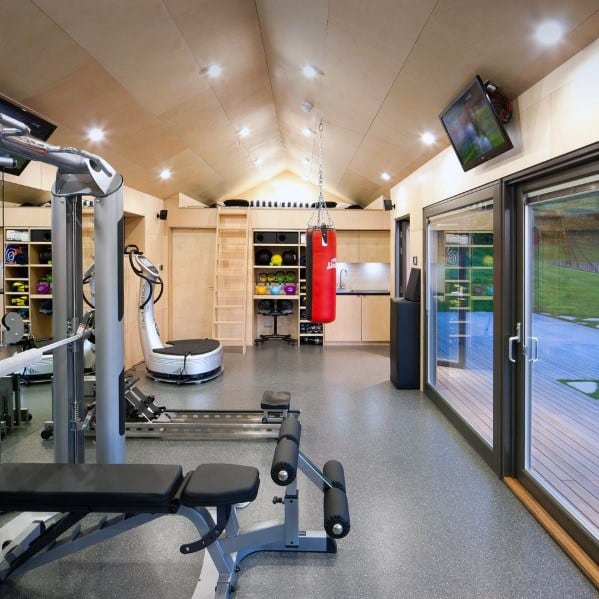 Spacious home gym with a punching bag, workout bench, bright lighting, and sliding glass doors.