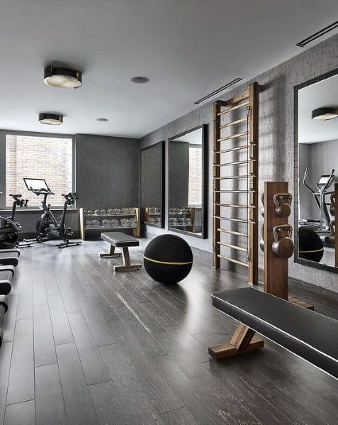 Sleek home gym with hardwood floors, wall mirrors, workout bench, kettlebells, and exercise bikes.