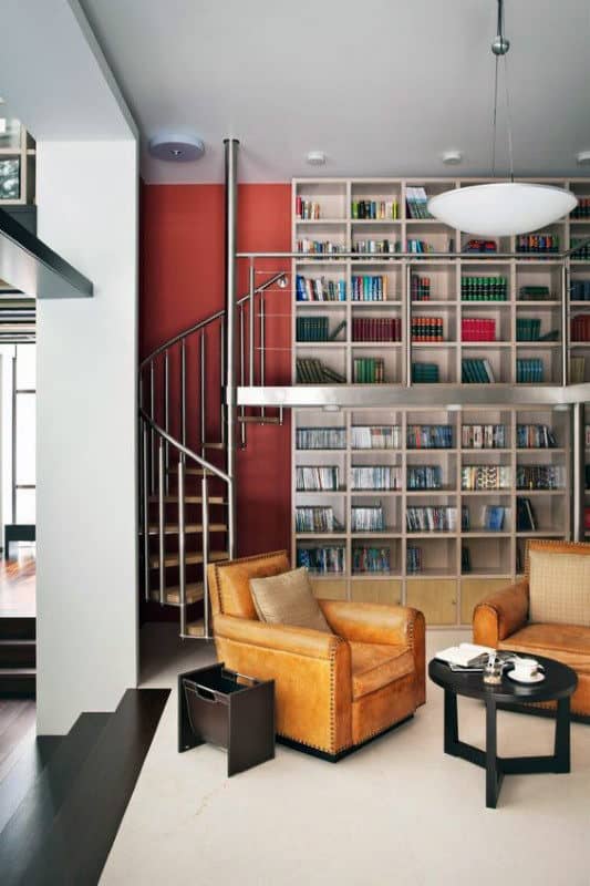 Cozy library with a spiral staircase, bookshelves, leather armchairs, and a round table with cups