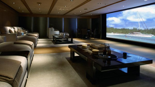 Luxurious home theater with plush seating and an ocean view screen featuring a sailboat