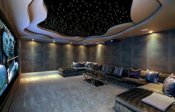 Home theater with a starry ceiling, large sectional sofa, and a movie projected on the big screen