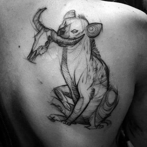 Sketch-style hyena tattoo on the shoulder, featuring the animal sitting and holding an antelope skull in its mouth with rough, artistic linework.