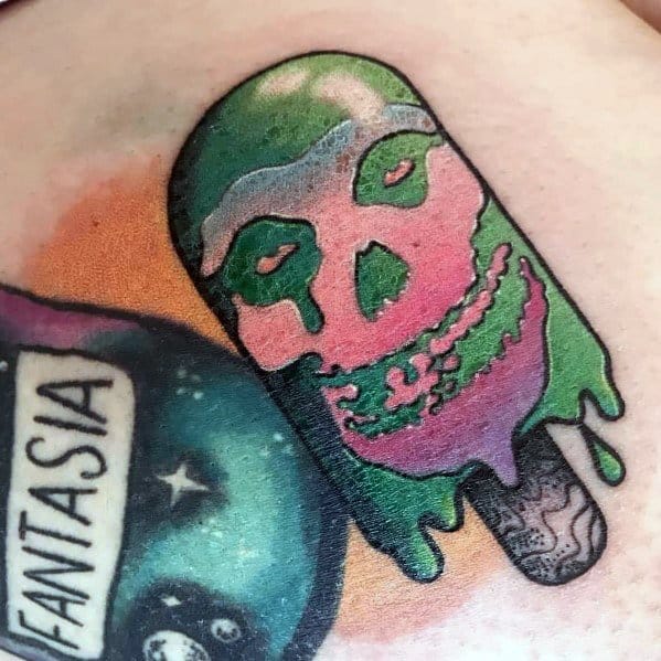 Colorful tattoo of a melting green and pink popsicle shaped like a skull, with bold outlines and dripping details for a spooky effect.