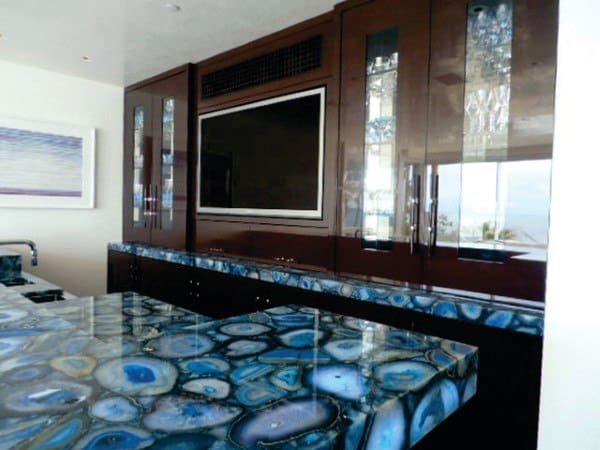 Polished blue agate bar top with dark wood cabinetry and built-in TV.