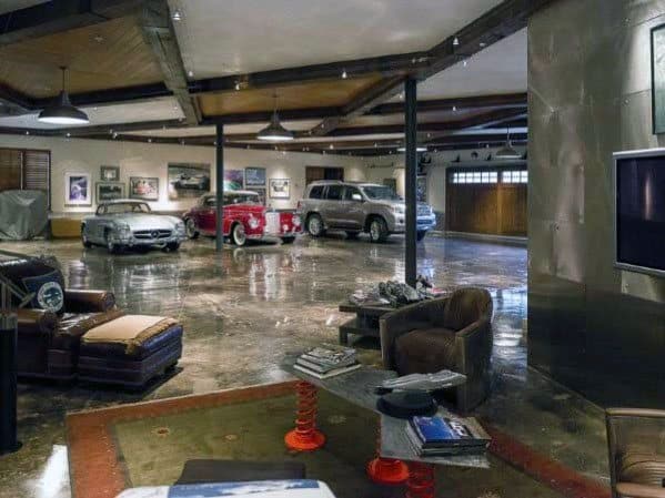 Luxury garage with polished floors, vintage cars, seating area, and decorative lighting.