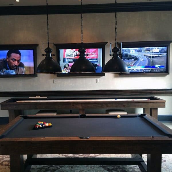 Pool table in a room with three TVs on the wall, showing different channels