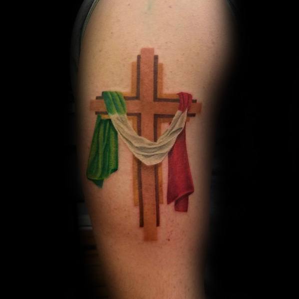 Cross tattoo on the upper arm with the Italian flag draped over it, symbolizing faith and heritage with realistic shading and details.